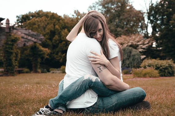Engaged couple are sitting in the ground in park in the summer. Photo by Ivan Djikaev.