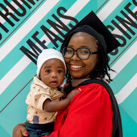A mom, graduating from business school, posing with her baby boy for graduation portrait