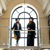 Two women, graduating from Suffolk University, posing on a balcony