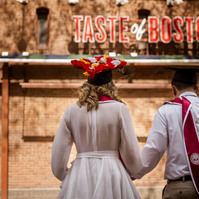 A view from the back of a couple in front of a Taste Of Boston sign