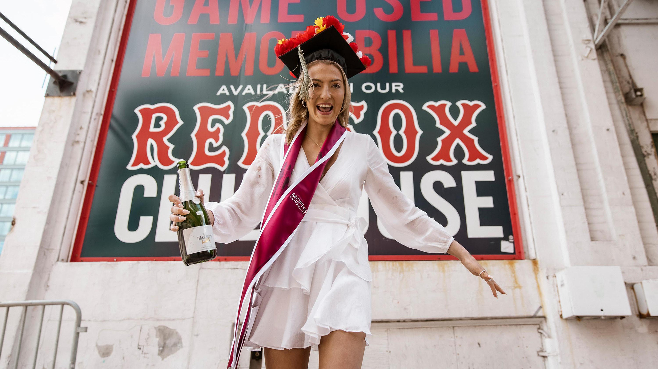 MCPHS University graduate with a bottle of Champaign at Fenway Park