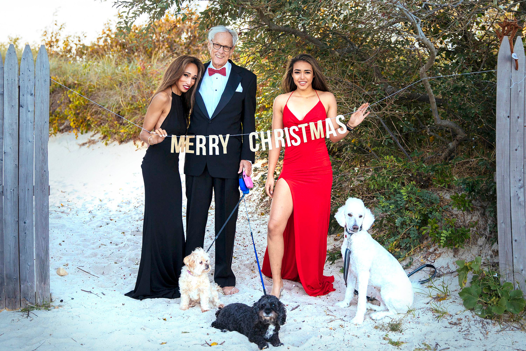 Family in evening dresses on the beach with a merry Christmas sign
