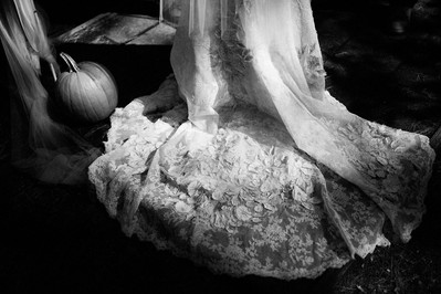 Fragment of a black and white Halloween bridal portrait, showing a train of a dress and a pumpkin. Photographer Ivan Djikaev/Mind On Photography.