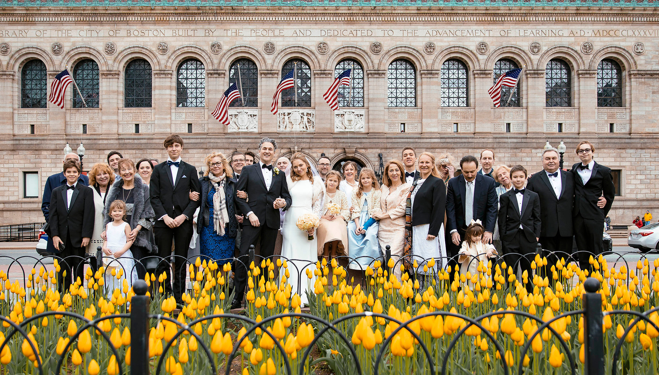 A whole wedding party is posing in front of Boston Public Library