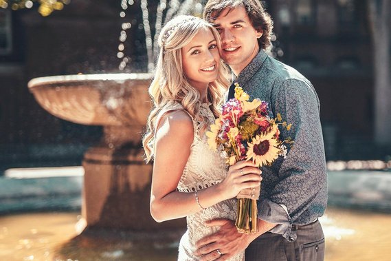 A bride and a groom are posing in front of a fountain in North End, Boston. Photo by Ivan Djikaev/Mind On photography.