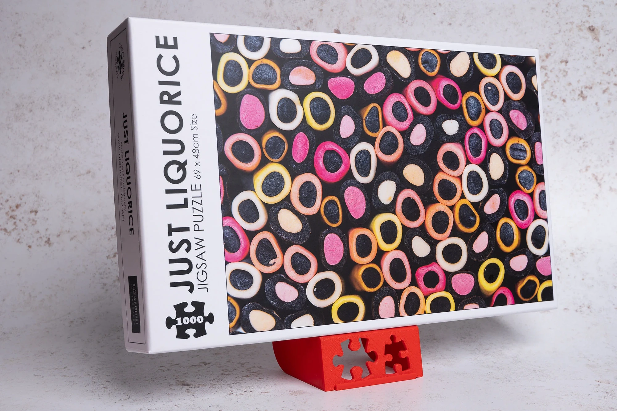 Jigsaw puzzle of Just Liquorice sweets propped up on a red plastic jigsaw lid holder stand 