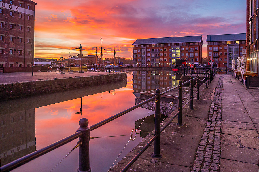 Sunset over Gloucester docks with reflection of sunbeams in the water, warm orange tones