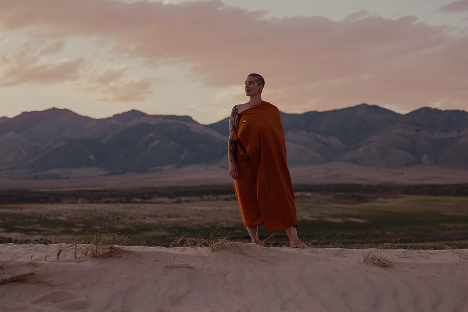 a buddhist monk in a yellow robe photographed by Cari Faye Antonovich of The White Room Studios at the Seminoe sand dunes near Rawlins Wyoming overlooking the ferris mountains at sunset