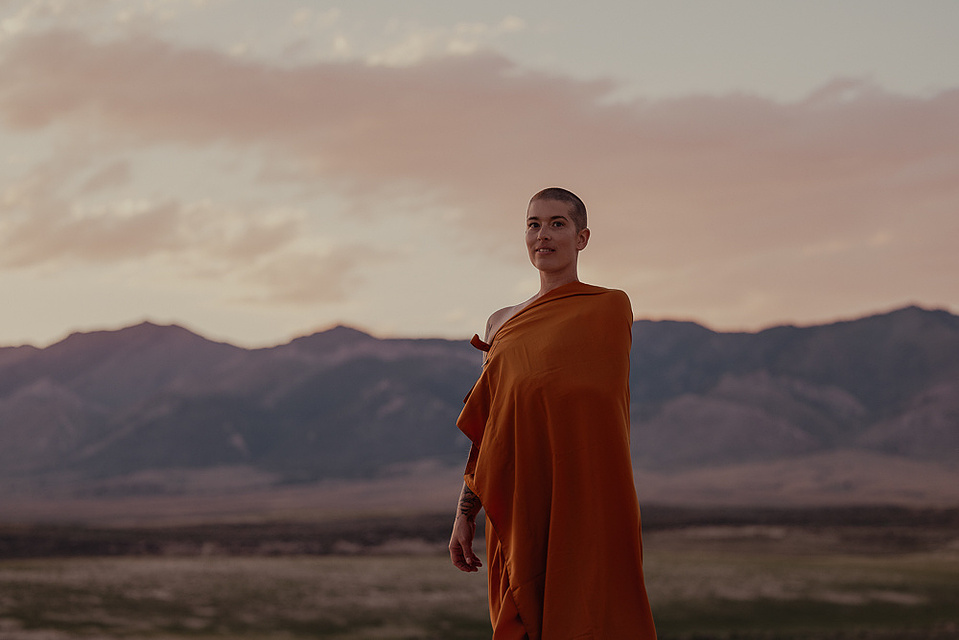 a buddhist monk in a yellow robe photographed by Cari Faye Antonovich of The White Room Studios at the Seminoe sand dunes near Rawlins Wyoming overlooking the ferris mountains at sunset