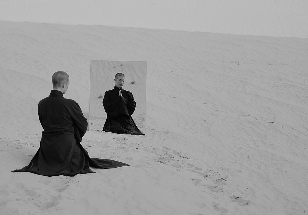 a buddhist monk in a red robe photographed by Cari Faye Antonovich of The White Room Studios at the Seminoe sand dunes near Rawlins Wyoming at sunset with a mirror