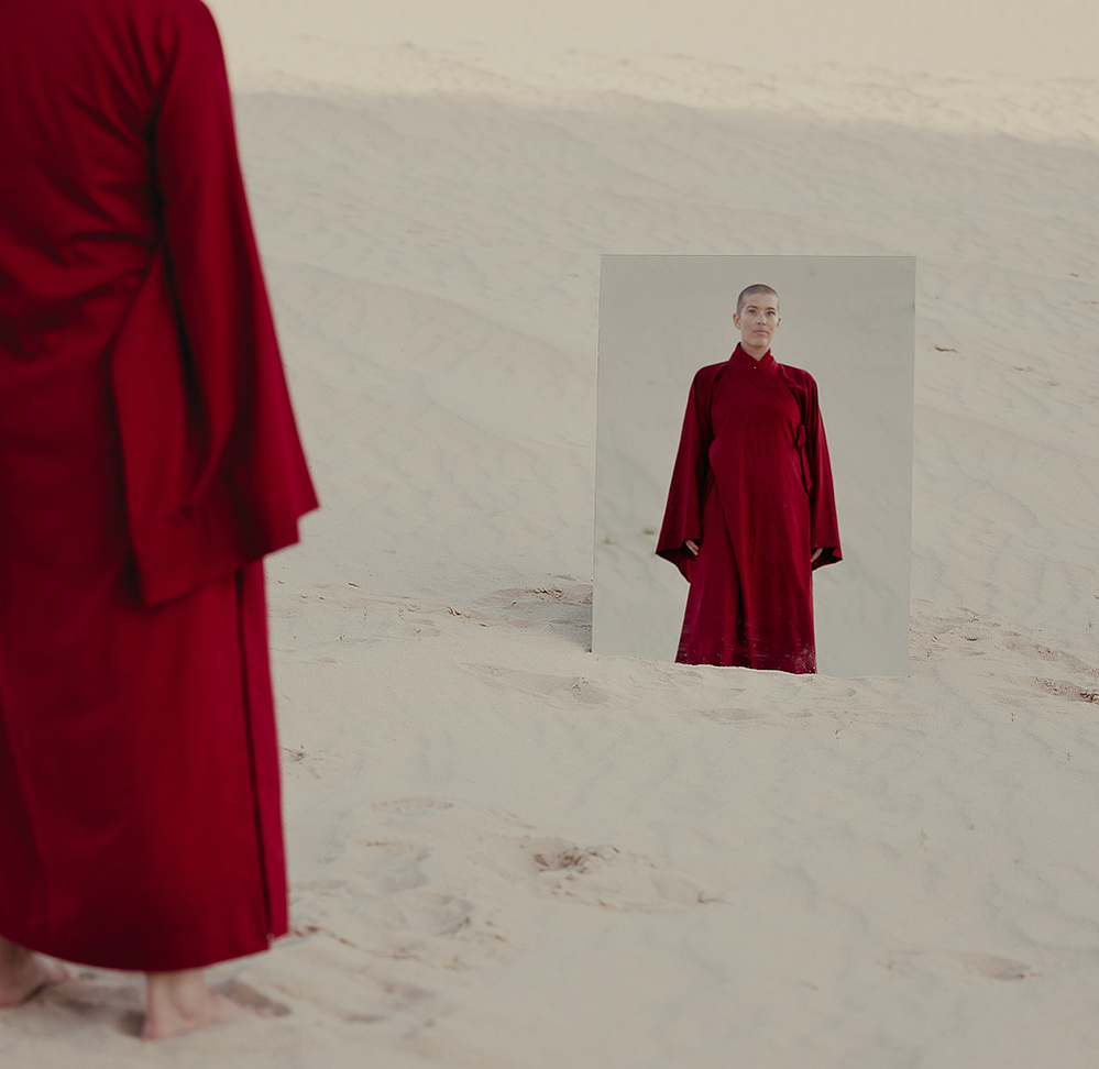 a buddhist monk in a red robe photographed by Cari Faye Antonovich of The White Room Studios at the Seminoe sand dunes near Rawlins Wyoming at sunset with a mirror