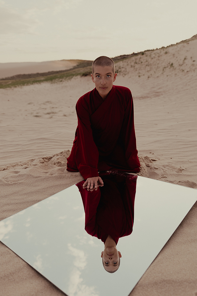 a buddhist monk in a red robe photographed by Cari Faye Antonovich of The White Room Studios at the Seminoe sand dunes near Rawlins Wyoming at sunset with a mirror