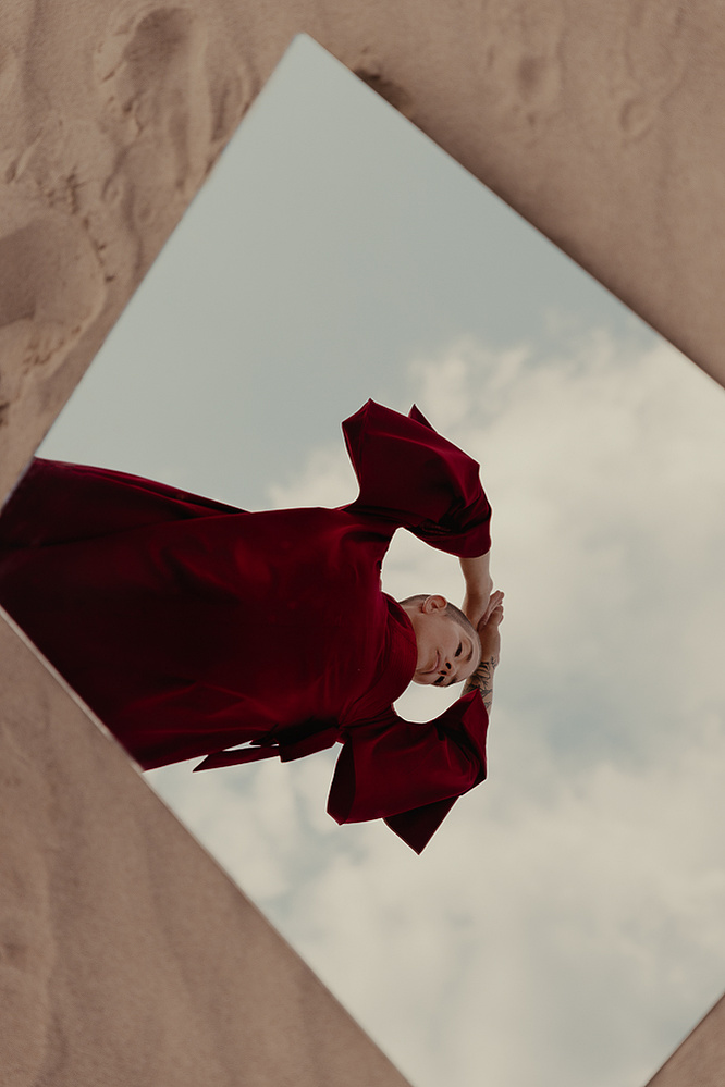 a buddhist monk in a red robe photographed by Cari Faye Antonovich of The White Room Studios at the Seminoe sand dunes near Rawlins Wyoming at sunset with a mirror