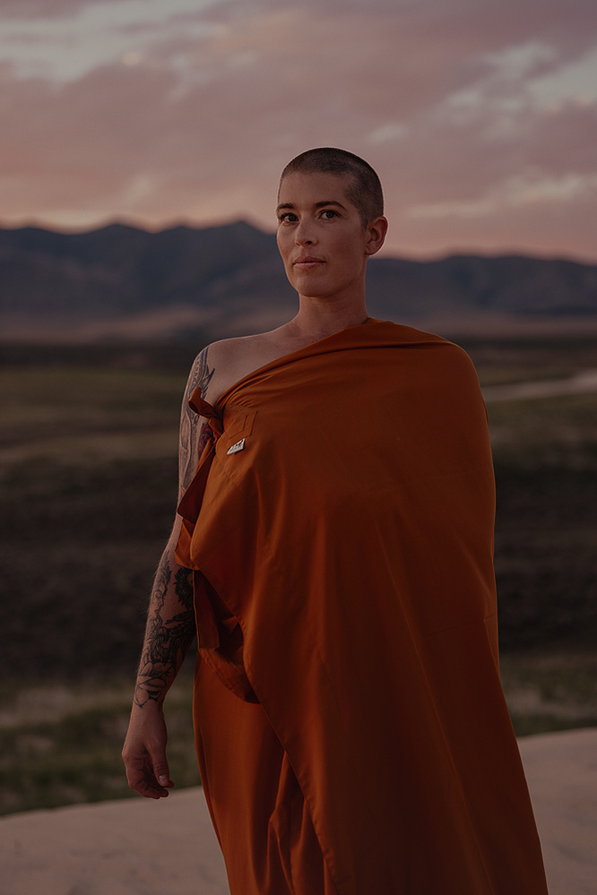 a buddhist monk in a yellow robe photographed by Cari Faye Antonovich of The White Room Studios at the Seminoe sand dunes near Rawlins Wyoming overlooking the ferris mountains at sunset