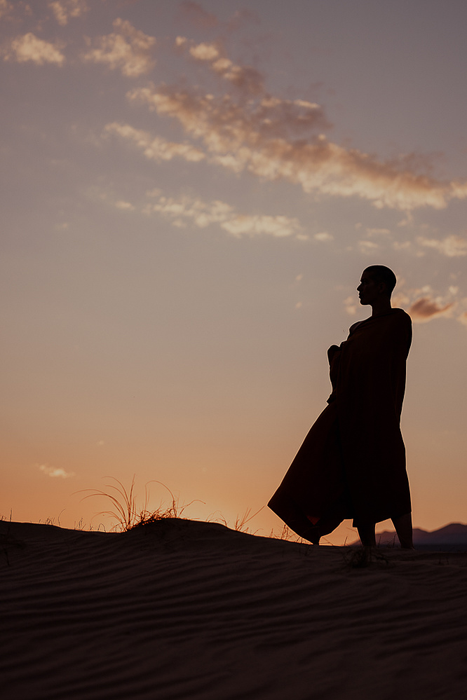 a buddhist monk in a yellow robe photographed by Cari Faye Antonovich of The White Room Studios at the Seminoe sand dunes near Rawlins Wyoming overlooking the ferris mountains at sunset
