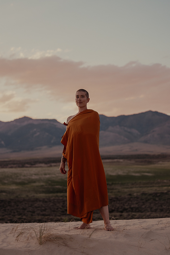 a buddhist monk in a yellow robe photographed by Cari Faye Antonovich of The White Room Studios at the Seminoe sand dunes near Rawlins Wyoming overlooking the ferris mountains at sunset