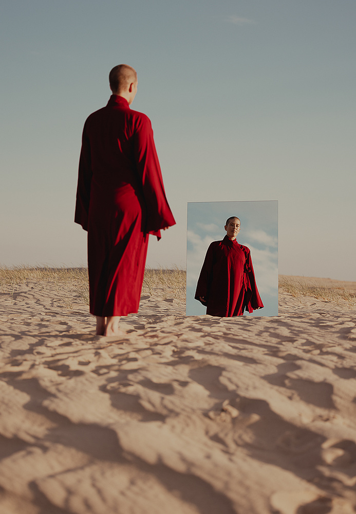 a buddhist monk in a red robe photographed by Cari Faye Antonovich of The White Room Studios at the Seminoe sand dunes near Rawlins Wyoming at sunset with a mirror