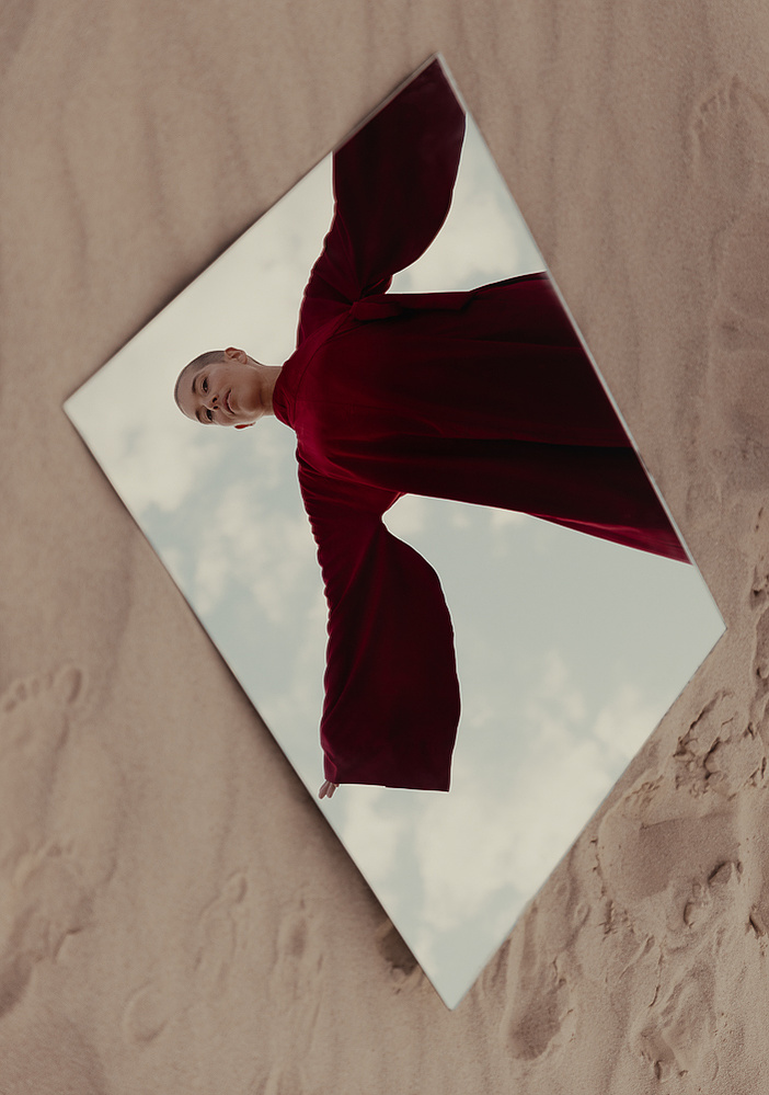 a buddhist monk in a red robe photographed by Cari Faye Antonovich of The White Room Studios at the Seminoe sand dunes near Rawlins Wyoming at sunset with a mirror
