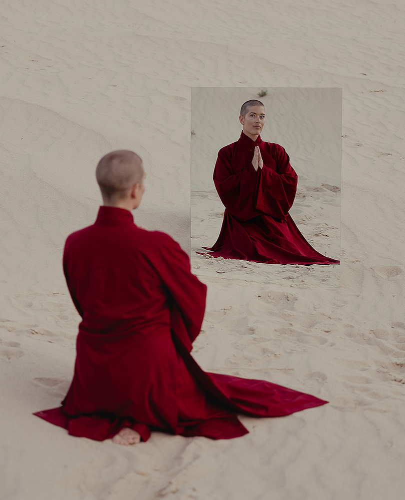 a buddhist monk in a red robe photographed by Cari Faye Antonovich of The White Room Studios at the Seminoe sand dunes near Rawlins Wyoming at sunset with a mirror