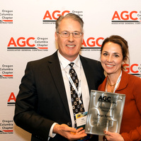 A woman stands in front of a step and repeat, receiving an award at the 2025 Associated General Contractors annual conference