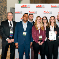 A group of people stand in front of a "step and repeat", receiving an award at the 2025 annual conference for AGC (Associated General Contractors)