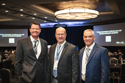 Three businessmen pose for a photo in the Portland Marriott Downtown Waterfront at the AAPA conference