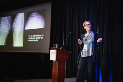 A woman on stage giving a presentation for AAPA at the Portland Marriott Downtown Waterfront