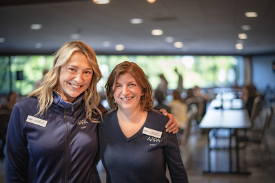 Two female co-workers standing side by side, posing for an image