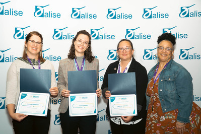 Four women showing their awards at the association for library information science & education conference in portland Oregon in front of a step and repeat