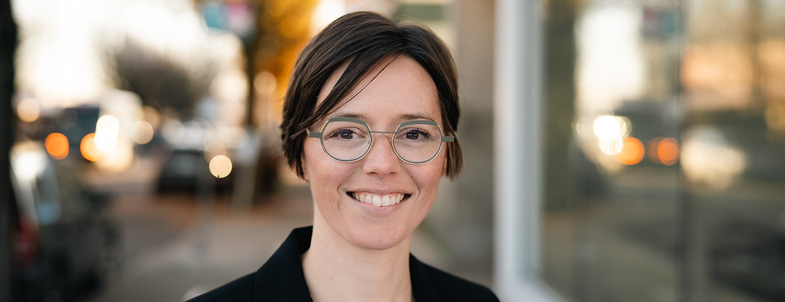 Outdoor headshot in Portland Oregon of a young white woman smiling and wearing a business jacket in the street