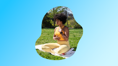 Liz C. meditating in the seated position in a grassy field.