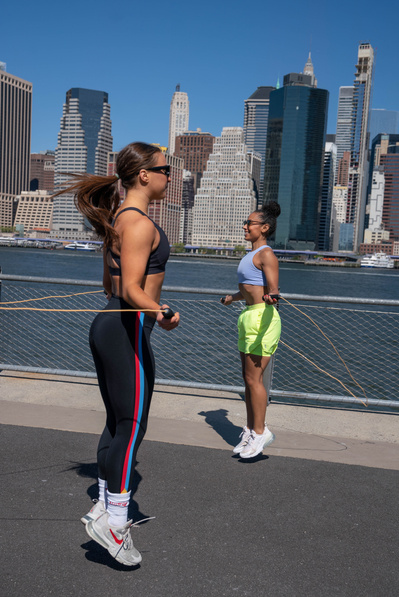 Two women jump roping in front of the New York City skyline.