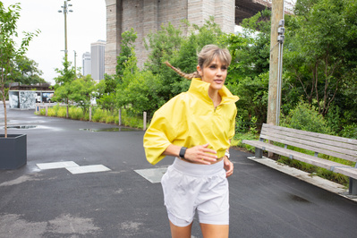 obé instructor Melody D. running outside in a yellow jacket.