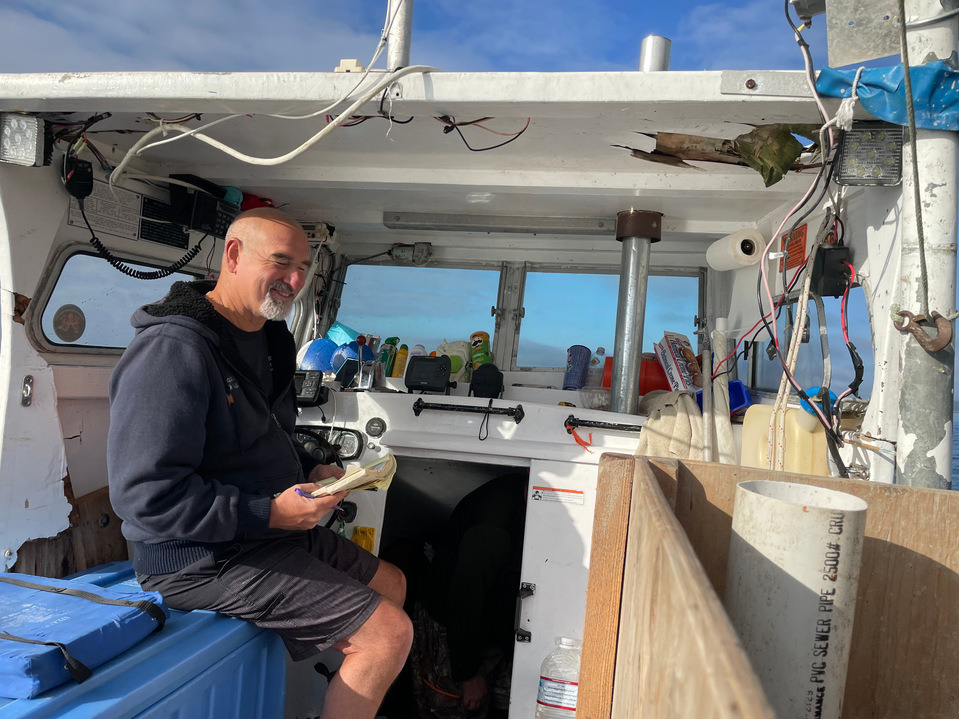 Captain and diver Chris Sparks sits in his boat on a September afternoon in 2021, preparing for a full day's work. The job involves diving to find sea cucumbers (mammals, not veggies) and bagging them so they can be hauled into the boat. 