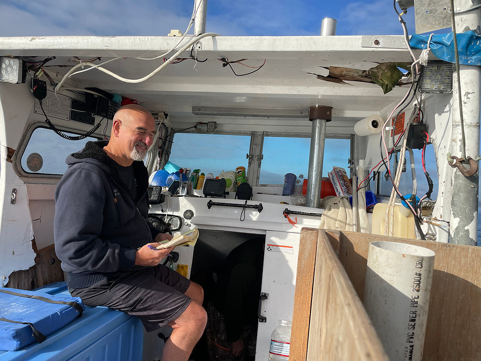 Captain and diver Chris Sparks sits in his boat on a September afternoon in 2021, preparing for a full day's work. The job involves diving to find sea cucumbers (mammals, not veggies) and bagging them so they can be hauled into the boat. 