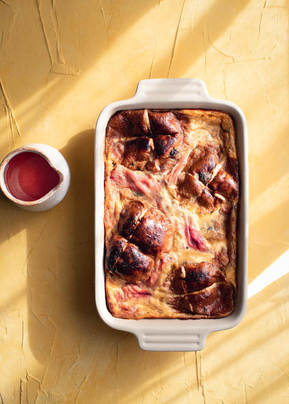 Elise Humphrey - food photographer - rhubarb hot cross bun and butter pudding on a painted yellow backdrop