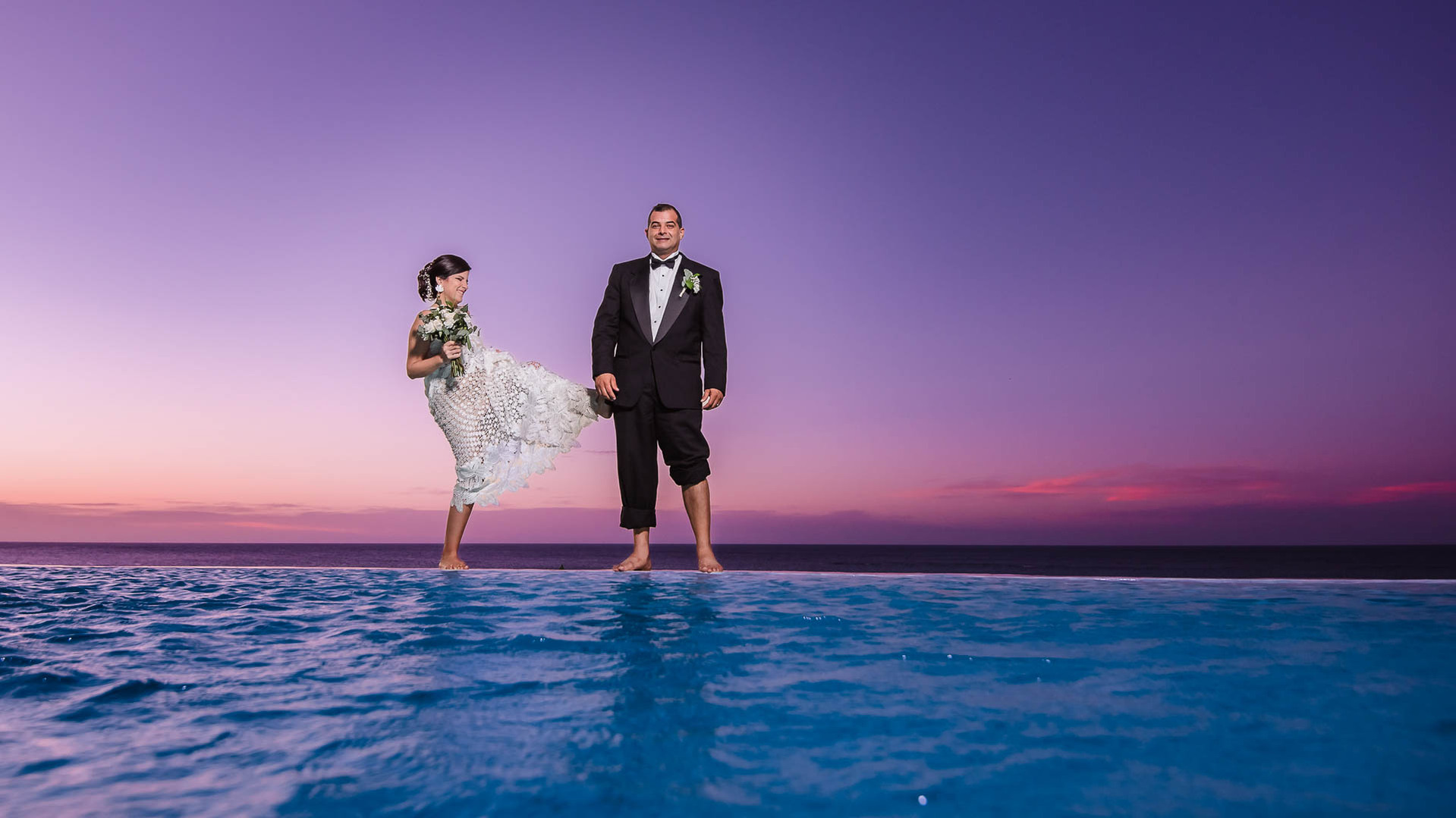 Bride and groom playing during sunset by the an infinity pool. Beach Destination Wedding Photography. 