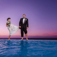 Bride and groom playing during sunset by the an infinity pool. Beach Destination Wedding Photography. 