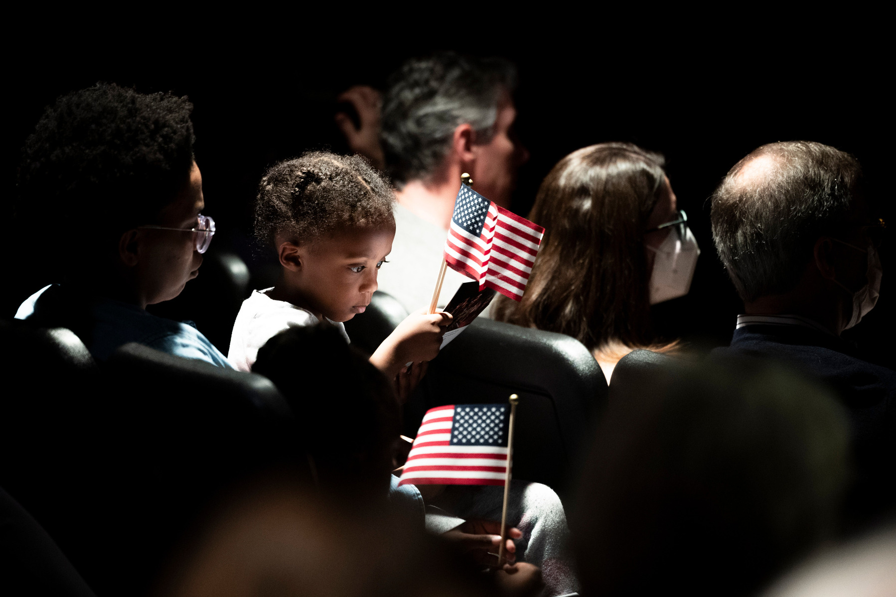 A child holds an American flag during a naturalization ceremony at the Virginia Museum of History & Culture in Richmond, Va., Monday, Feb. 19, 2024. 