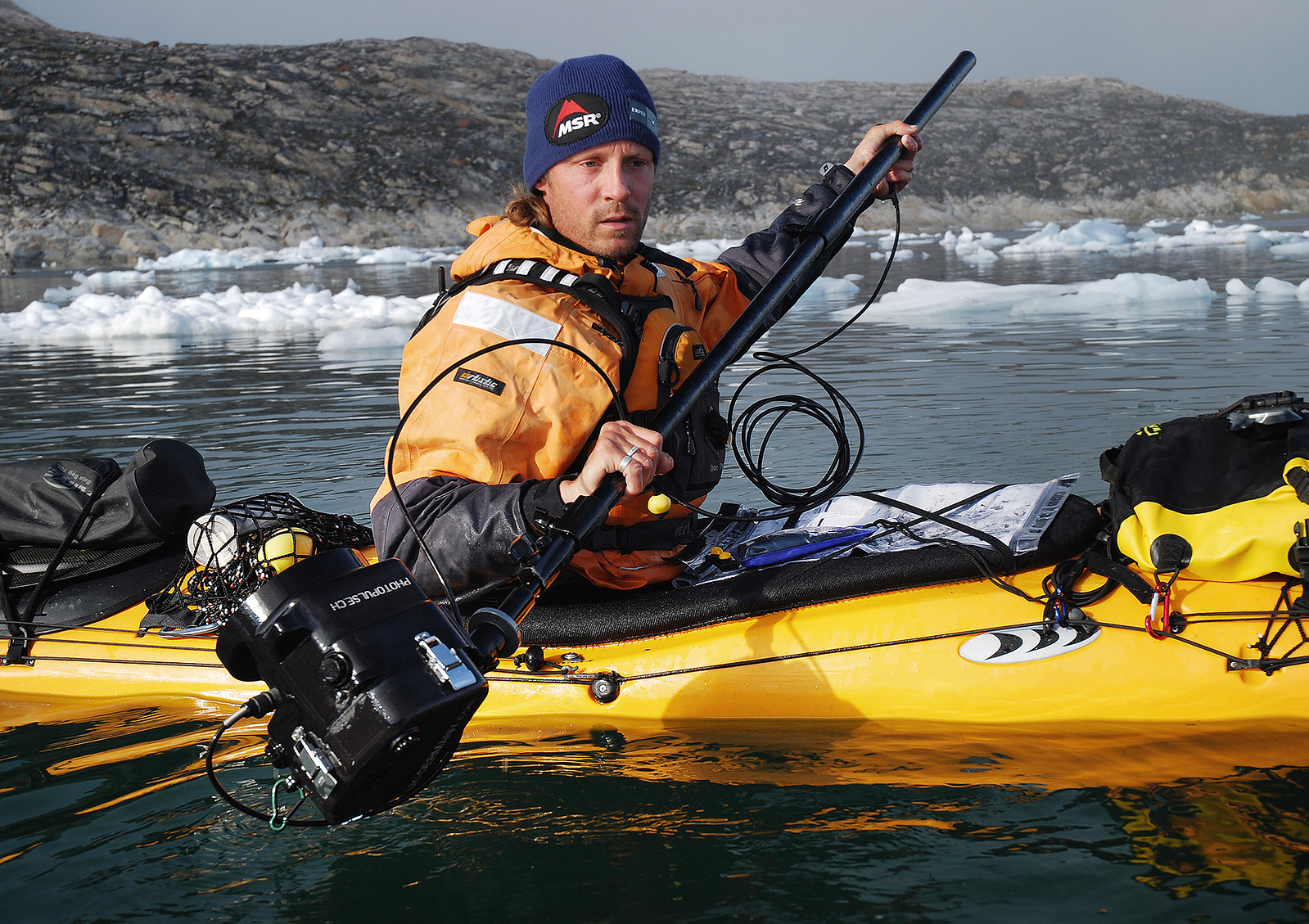 Adventure and outdoor photographer in his kayak preparing his equipment for an underwater shot.