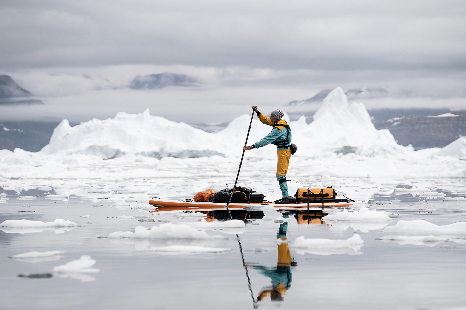 Adventure and outdoor photographer paddling on is stand up paddle board in North Greenland to create visual content.