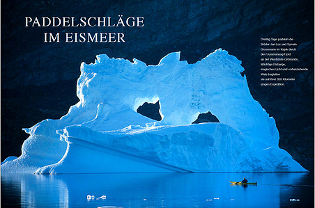 Publication tearsheet of a spread page showing a kayaker paddling in front of a huge iceberg with two arches early morning in Greenland.