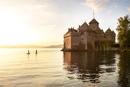 Travel photographer Switzerland – Chateau chillon at sunset with 2 stand up paddlers.