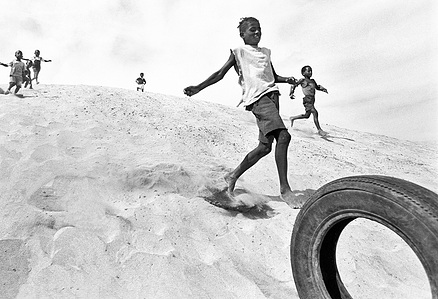 Reportage and travel photographer Switzerland – children playing with tire in sand dunes, Cape Verde.