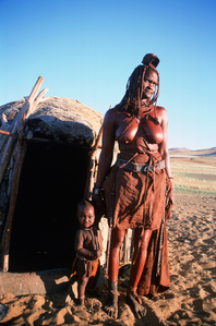 Himba woman standing in front of her hut.