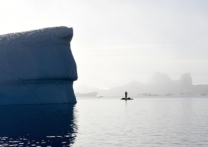 Lonely stand up paddler surrounded by iceberg on a foggy day in north west Greenland – Stand up paddling expedition.
