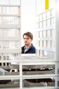 Philip de Vries von Seleform am Stand von Inch Furniture vor einem Modell der neuen Fachhochschule Nordwestschweiz (FHNW) in Muttenz, Schweiz