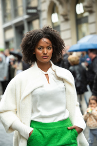 Black model with white top and green pants walking for a fashion show in the streets of Basel.