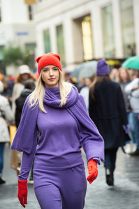 Model with pink clothes and ret beanie walking for a fashion show in the streets of Basel.