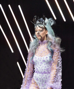 Model in a fashion dress and with a hat walking on the cat walk.